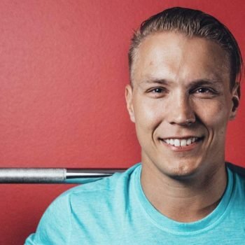 iloinen mies kuntosalilla tanko hartioillaan