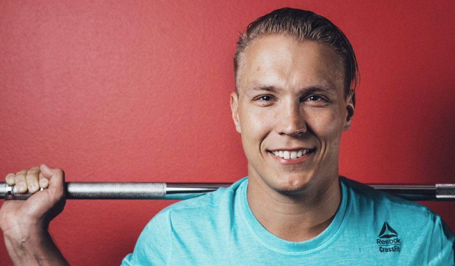 iloinen mies kuntosalilla tanko hartioillaan